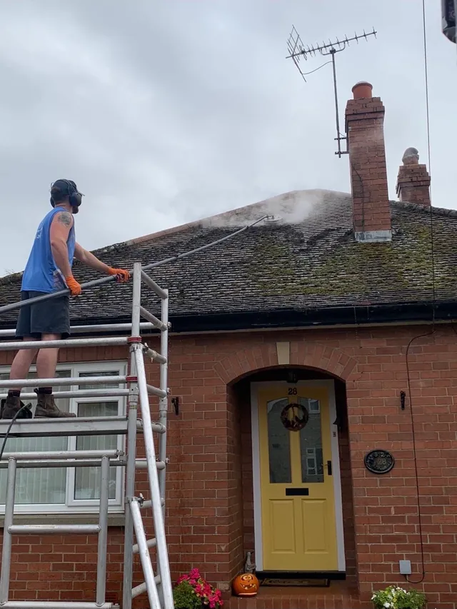 Roof cleaning in progress on a brick house