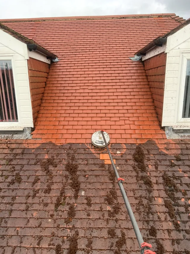 Roof-cleaning equipment working across red roof tiles
